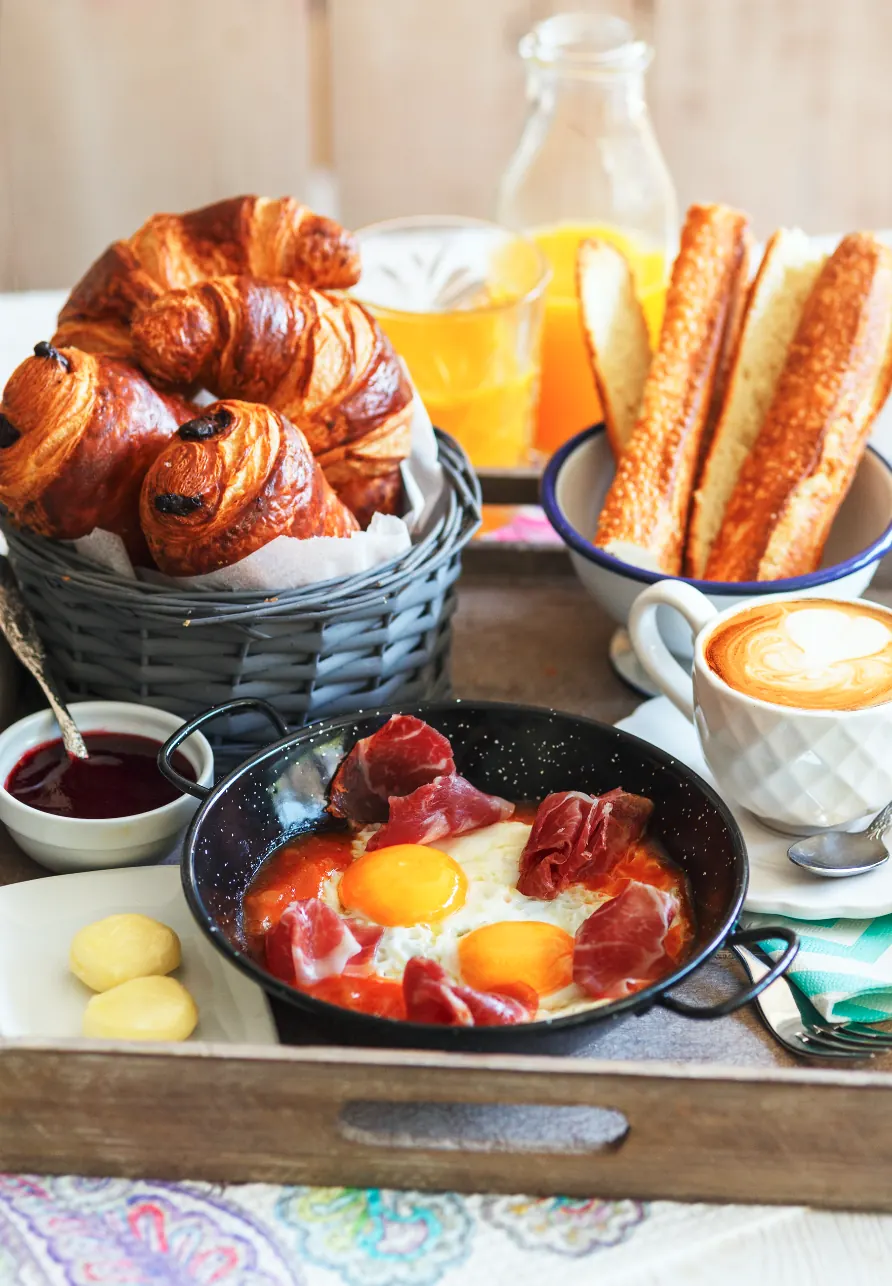 Esmorzar amb croissants, torrades, suc de taronja, cafè i ous amb pernil