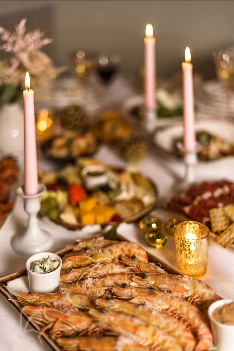 Mesa de Navidad con gambas, velas rosas y platos para compartir